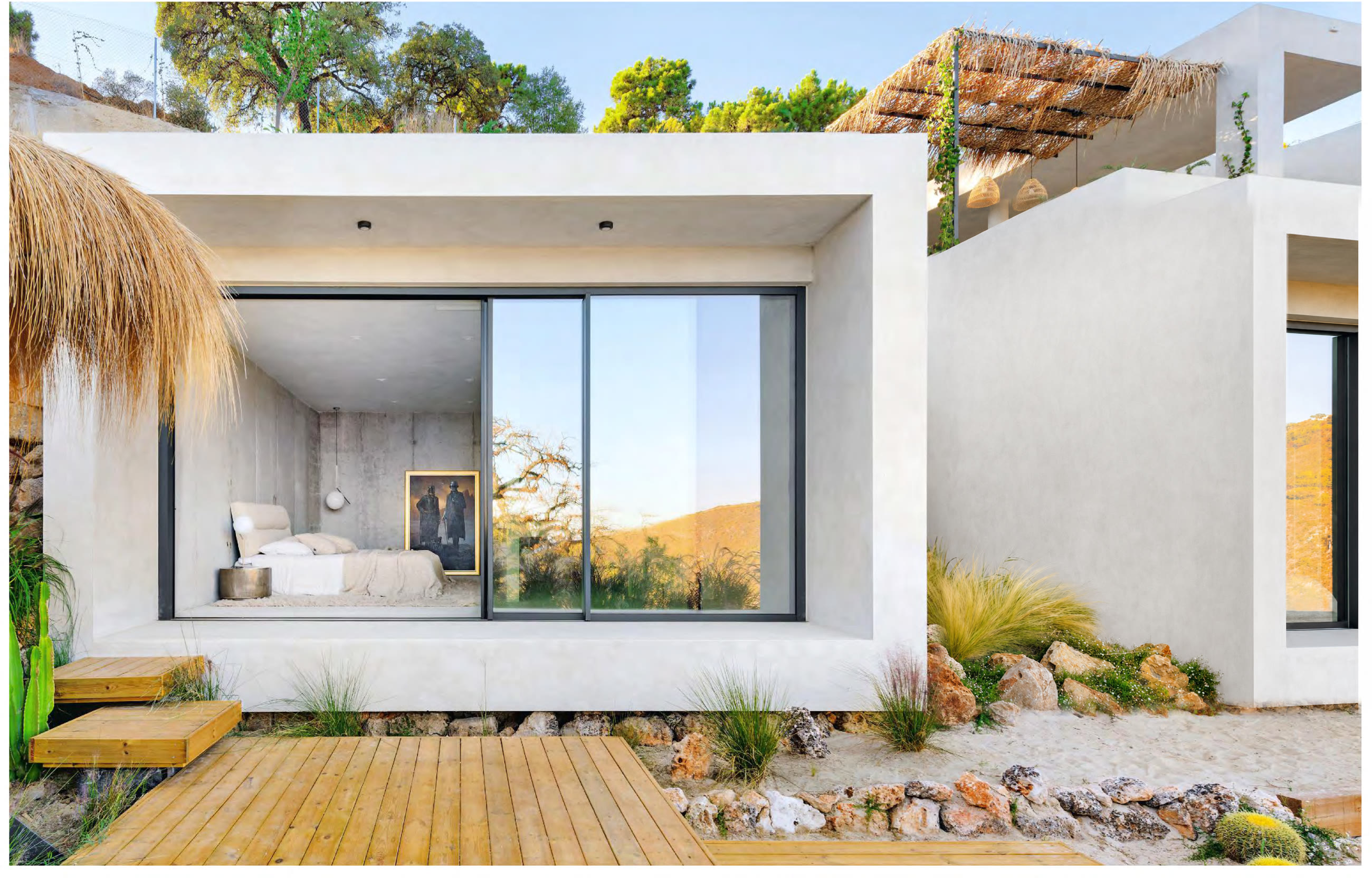 The two guest bungalows in the white-sand garden — raw concrete, timber walkway, straw pergola