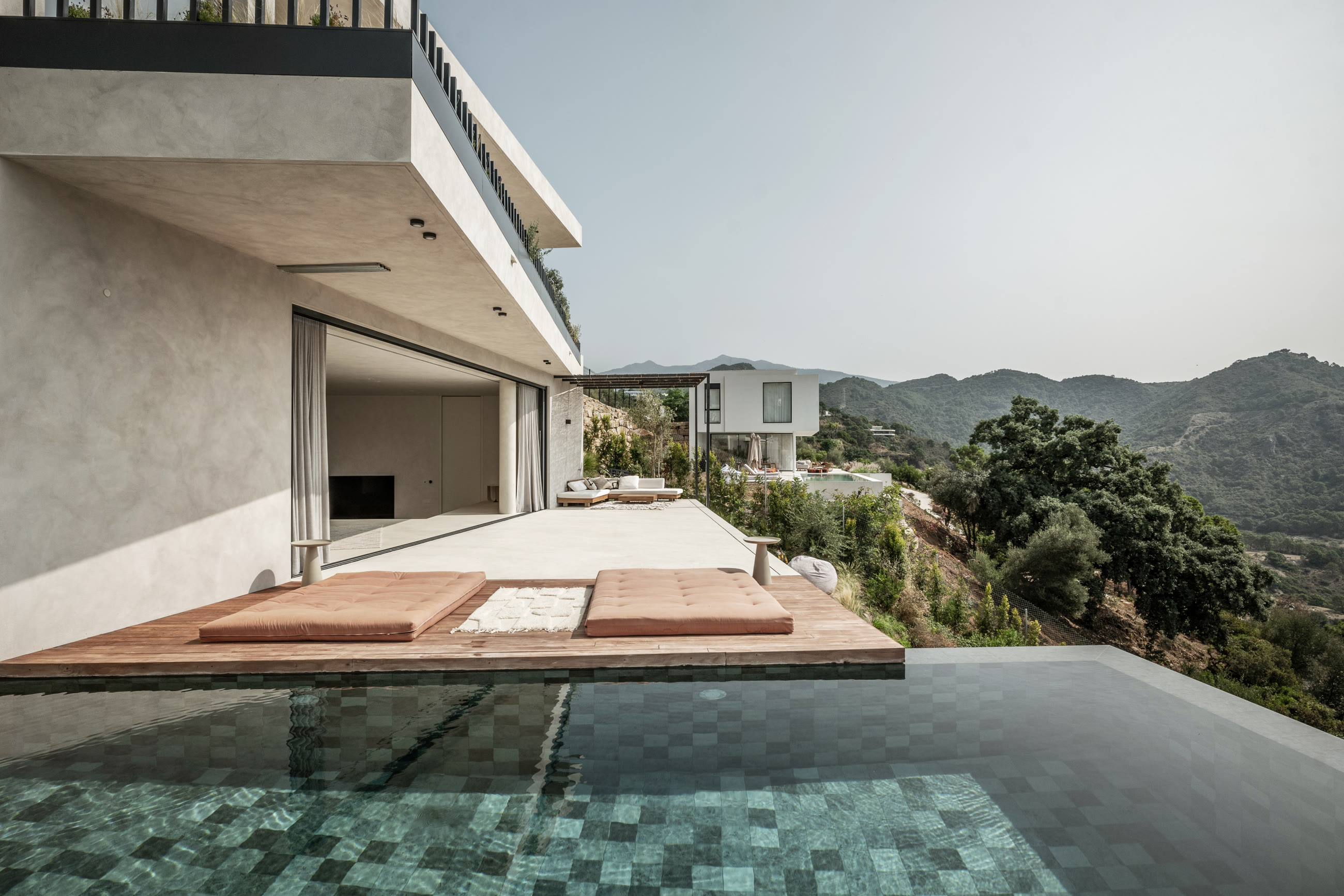 The green-mosaic infinity pool of Casa Jaguar with the living room open behind it